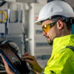 man-electrical-technician-working-switchboard-with-fuses-uses-tablet-compressed