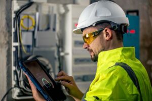 man-electrical-technician-working-switchboard-with-fuses-uses-tablet-compressed